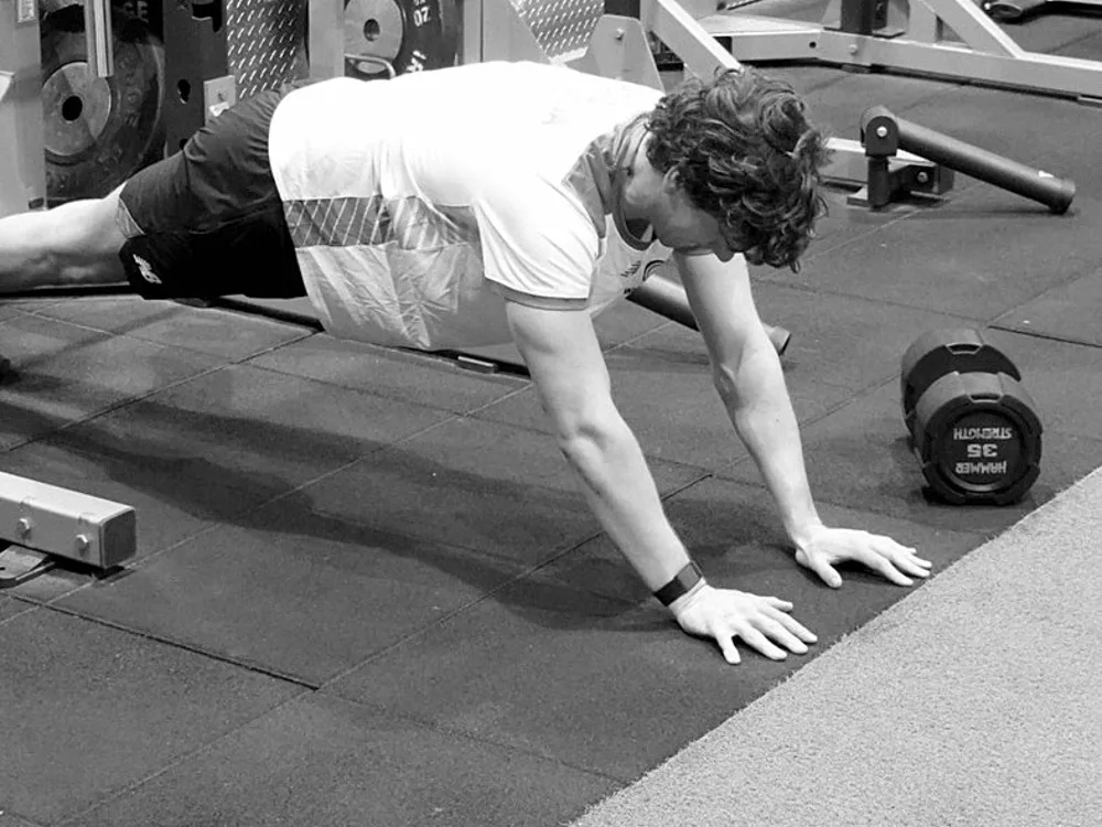 An athlete training in a gym with a weight rack